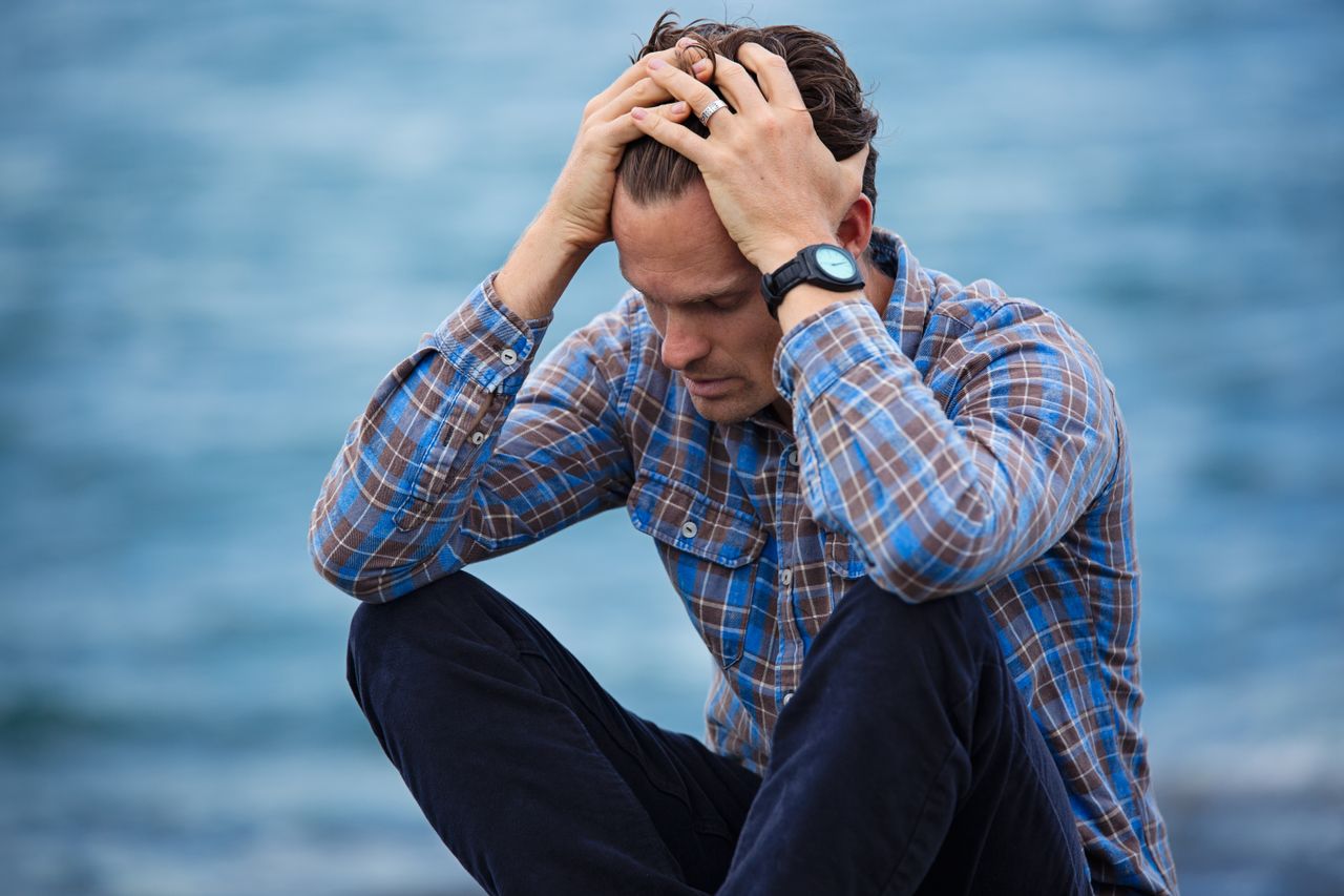 Depressed man sitting at a beach.